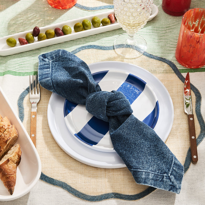 White ceramic olive serving tray with green and purple olives, part of a table setting.